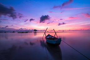 Ein Boot auf einem See beim lila Sonnenuntergang